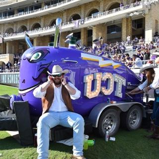 A large purple train horn mounted on a trailer with the "TCU" logo lit up in bright white lights