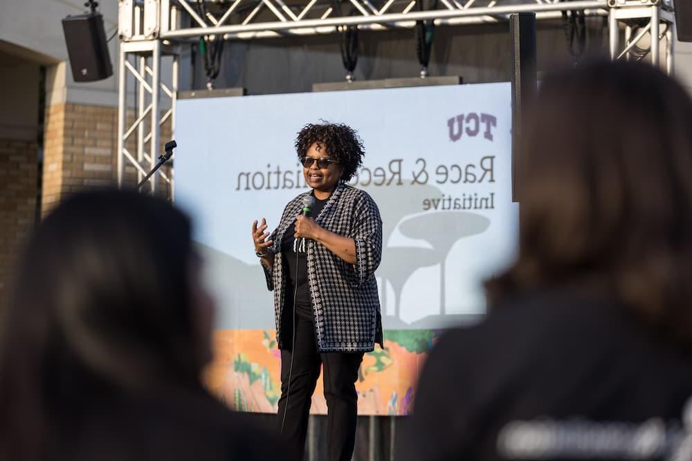 Dr. Amiso George speaks on stage to a crowd